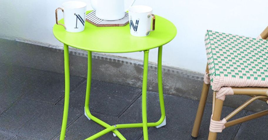 Metal Outdoor Patio Accent Table in Lime Green sitting outside by a green and white wooden chair