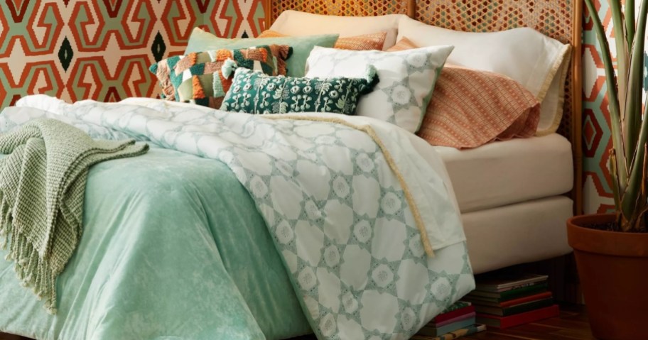 bed with a light green velvet reversable duvet cover and shams and decorative pillows