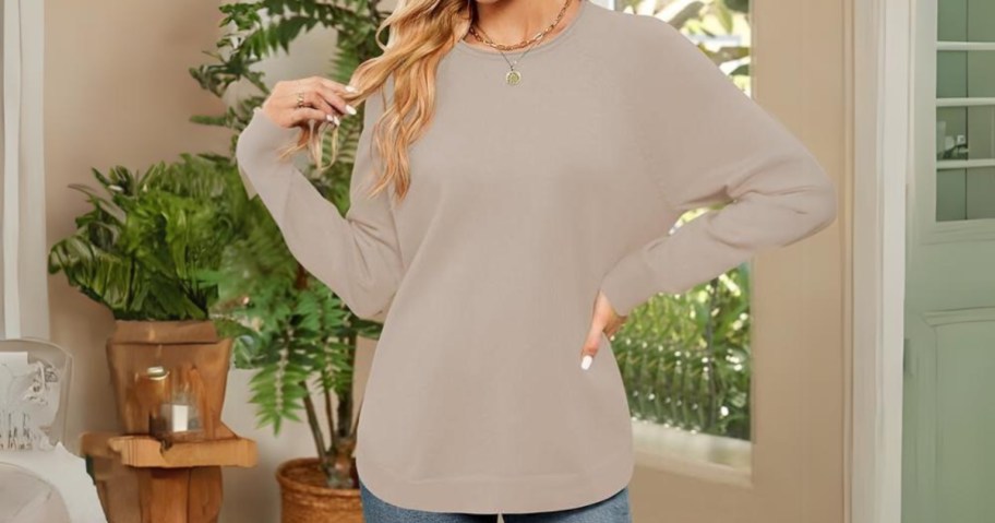 woman wearing a tan color oversized crew neck sweater