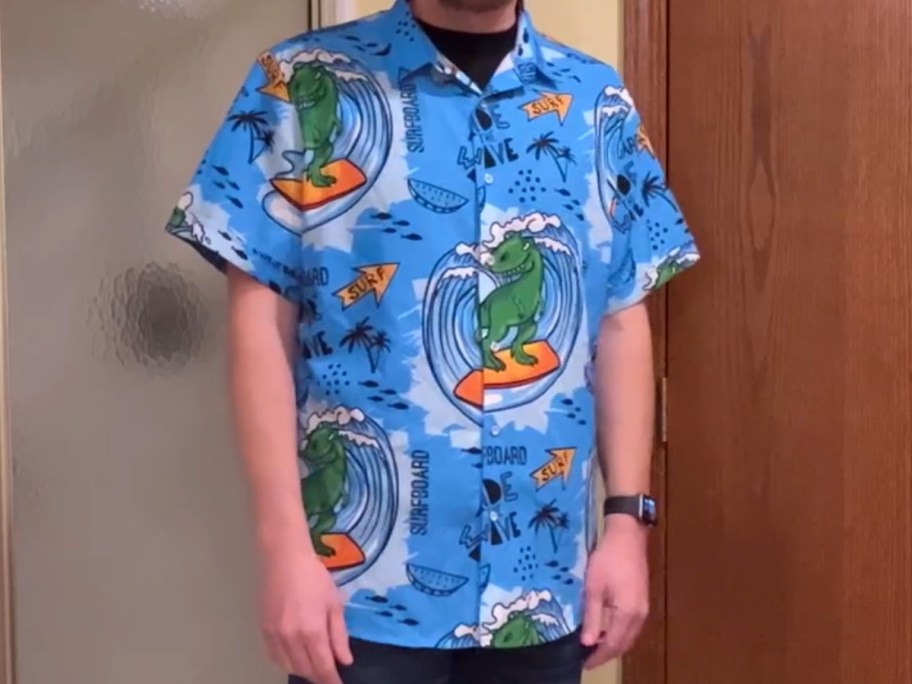 man wearing a blue Hawaiian shift with surfing dinosaurs on it