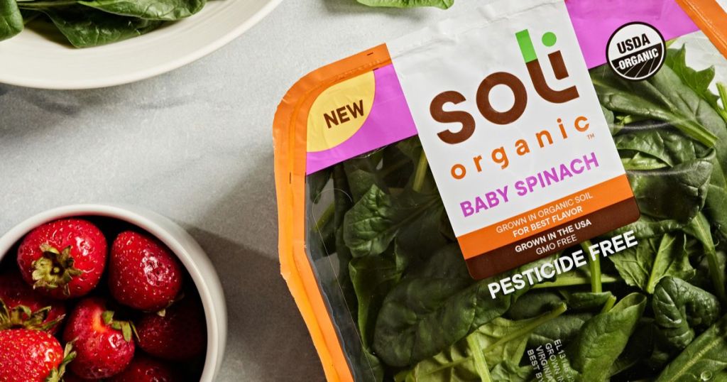 package of soli organic salad baby spinach beside a bowl of berries