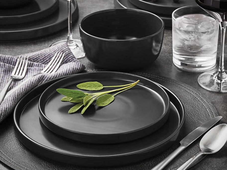 set of black stoneware dishes and bowls on a kitchen table