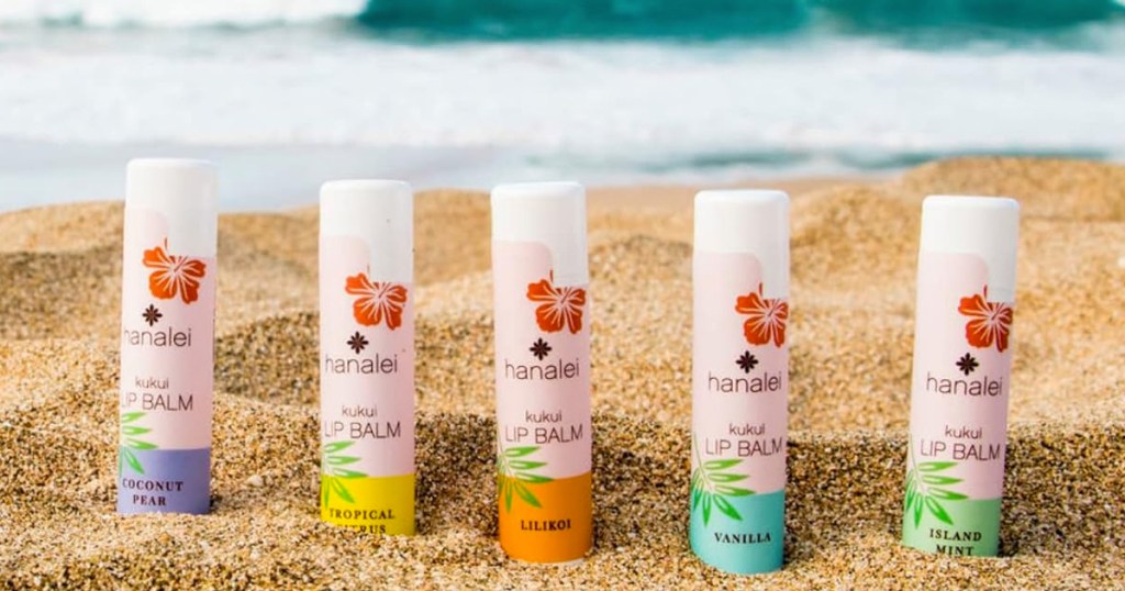 5 tubes of Hanalei Lip Balms in sand at beach