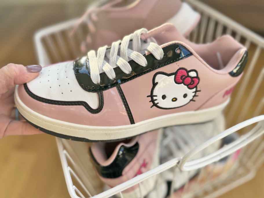 hand holding a pink, black, and white hello kitty sneaker