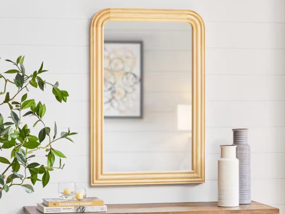 arched wall mirror with wood frame above console table