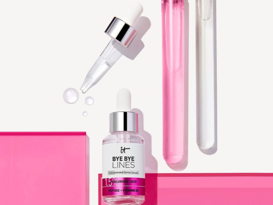 A bottle of It cosmetics Bye Bye Lines with the dropper cap removed and a couple drops of the serum next to it