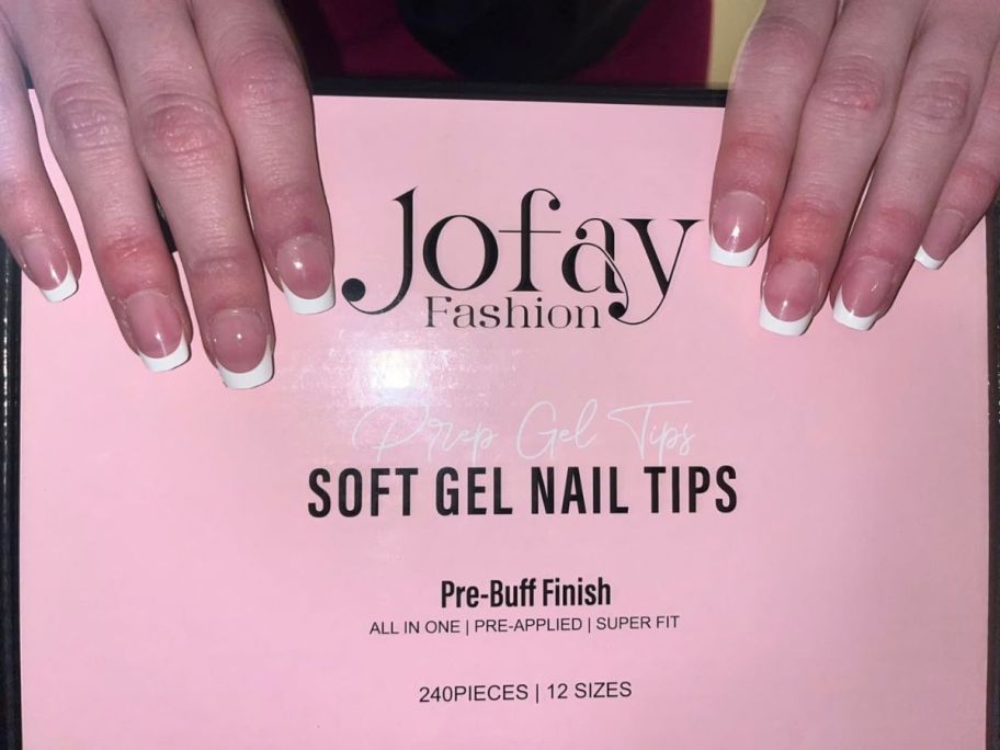 Hand holding a box of Jofay gel nail tips with perfectly manicured french tip nails