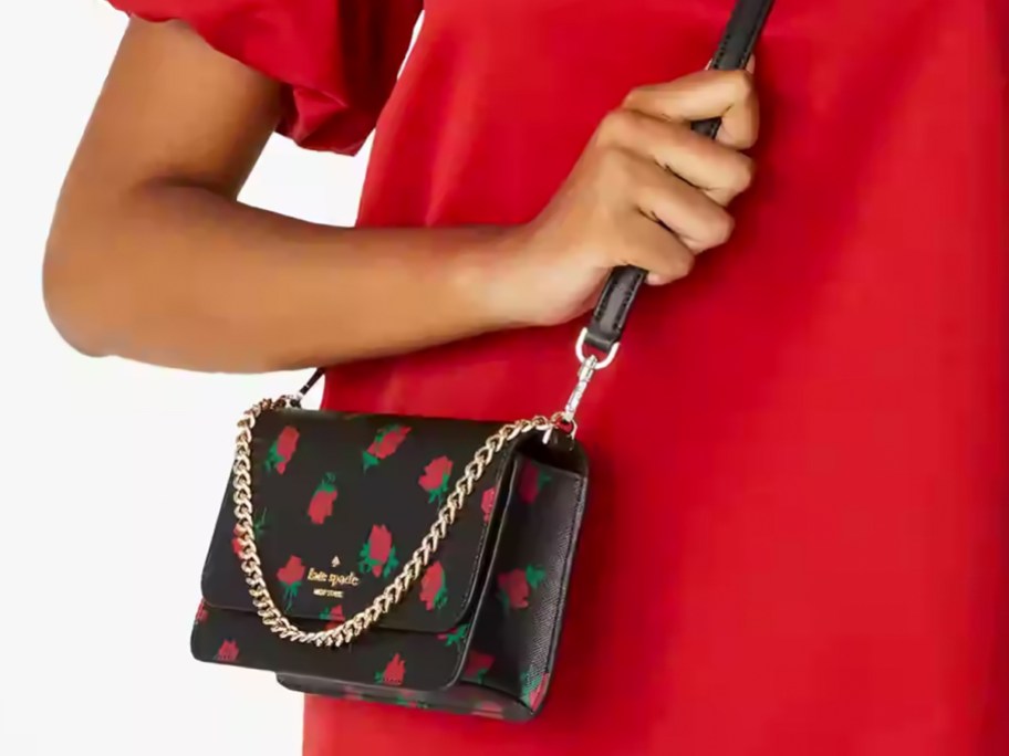 woman in red top with black and red rose print crossbody bag