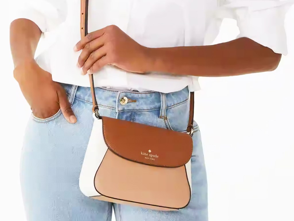 woman in light jeans and white top with brown and white colorblock crossbody bag