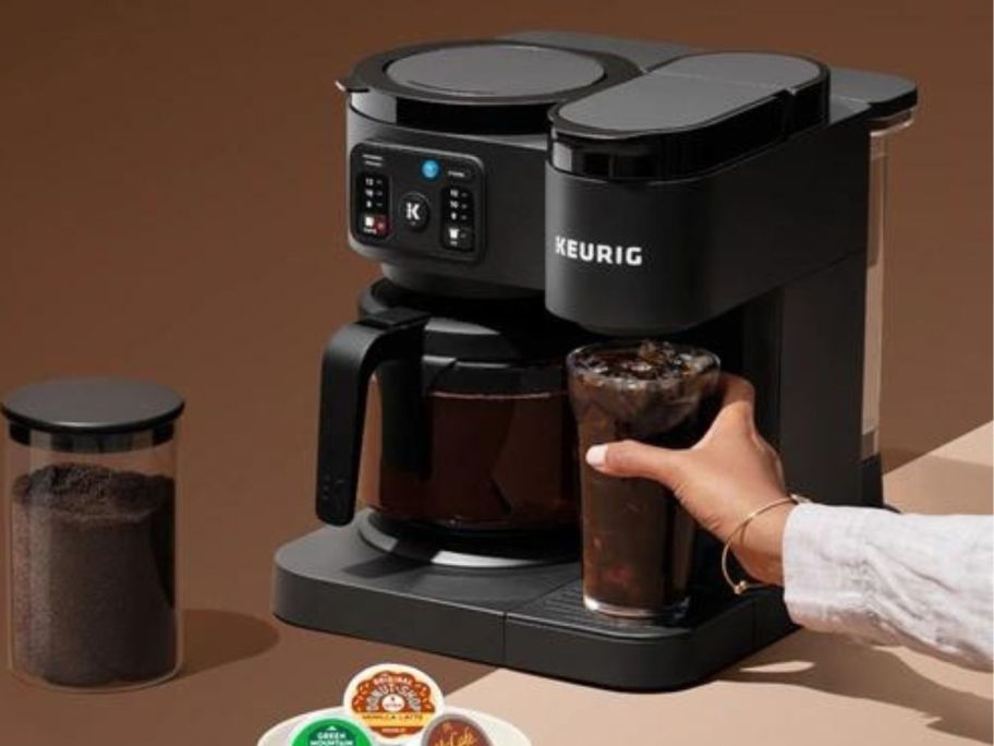 Keurig K-Duo Essentials Single Serve K-Cup Pod & Carafe Coffee Maker with hand reaching for filled cup