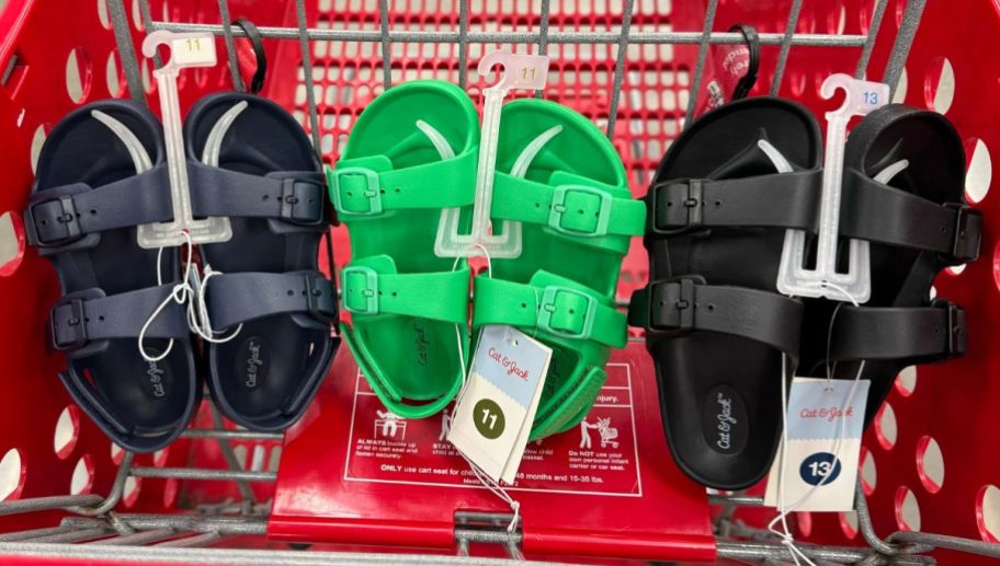3 pair of Cat and Jack kids footbed sandals in navy, green and black lined up in a row in a target shopping cart