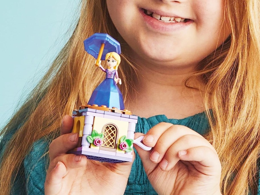 girl holding a LEGO Rapunzel toy