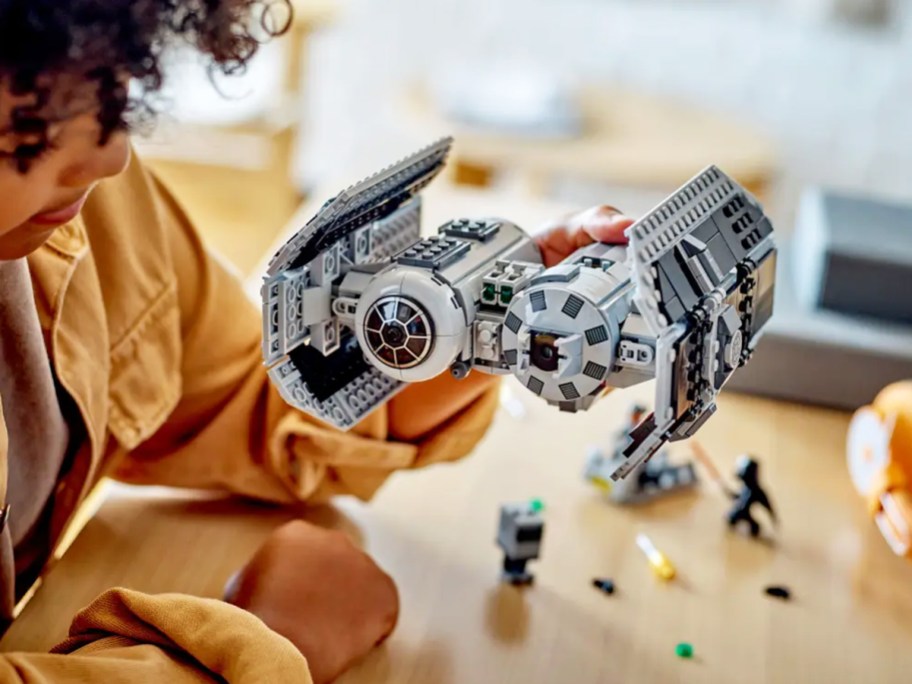 boy holding up a LEGO Star Wars TIE Bomber Model Building Kit