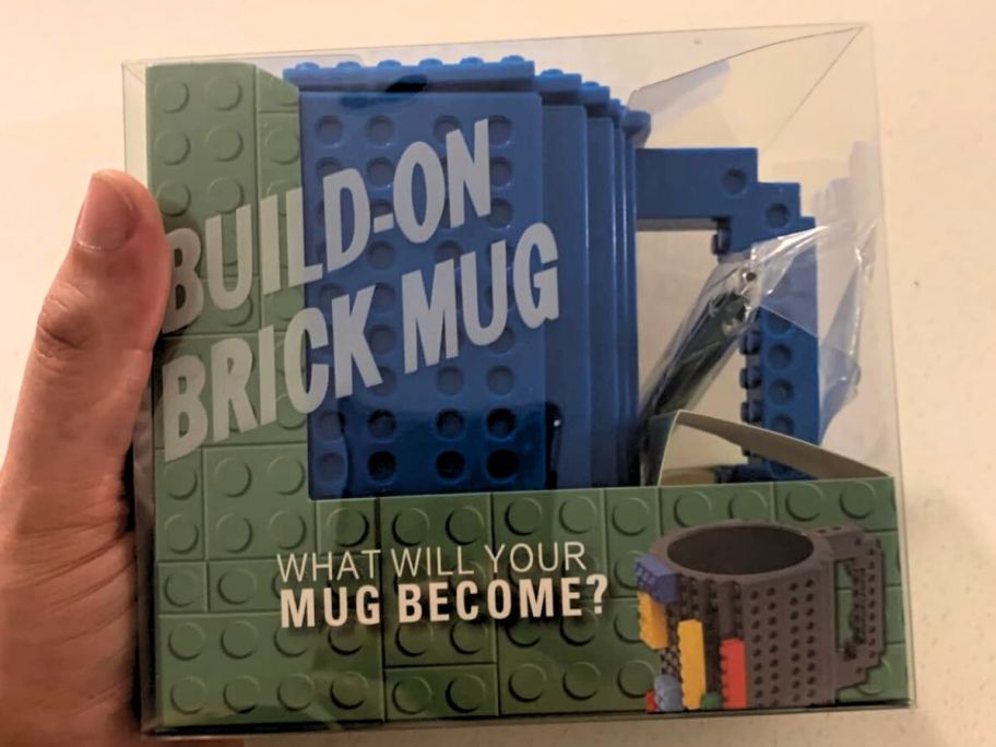 Hand holding a box with a LEGO style build on brick mug inside