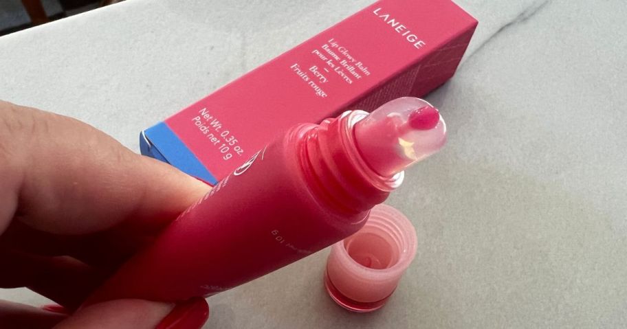 Hand squeezing some glowy balm out of a tube of Laneige