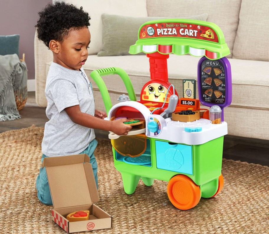 boy kneeling on floor and playing with LeapFrog Build-a-Slice Pizza Cart