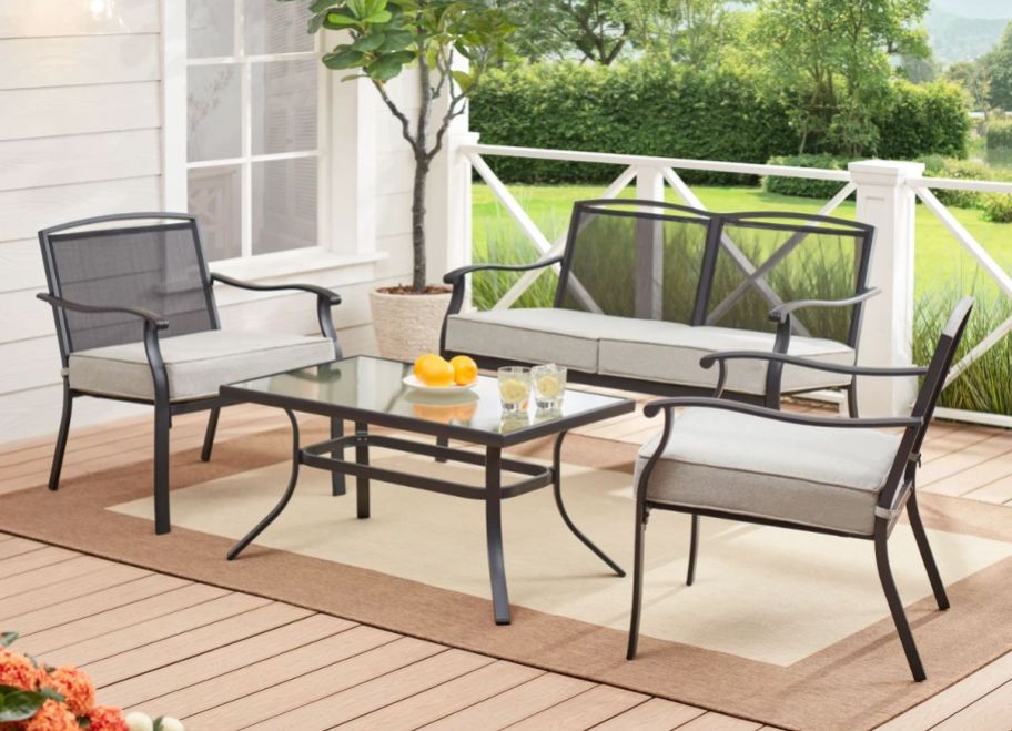 a four piece outdoor patio set with gray cushions set up on a deck