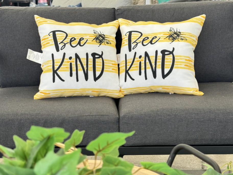 yellow and white throw pillows that say "bee kind" on outdoor couch