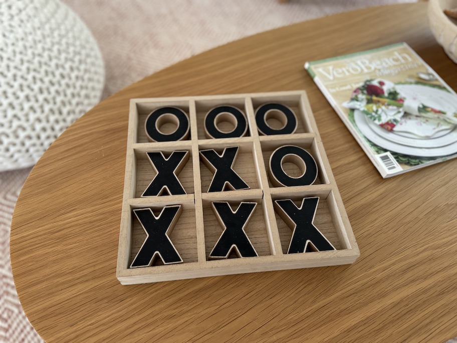 wooden tic tac toe game with dark brown x and os on wood table