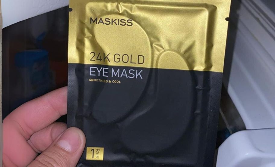 a hand holding a packet gold eye masks