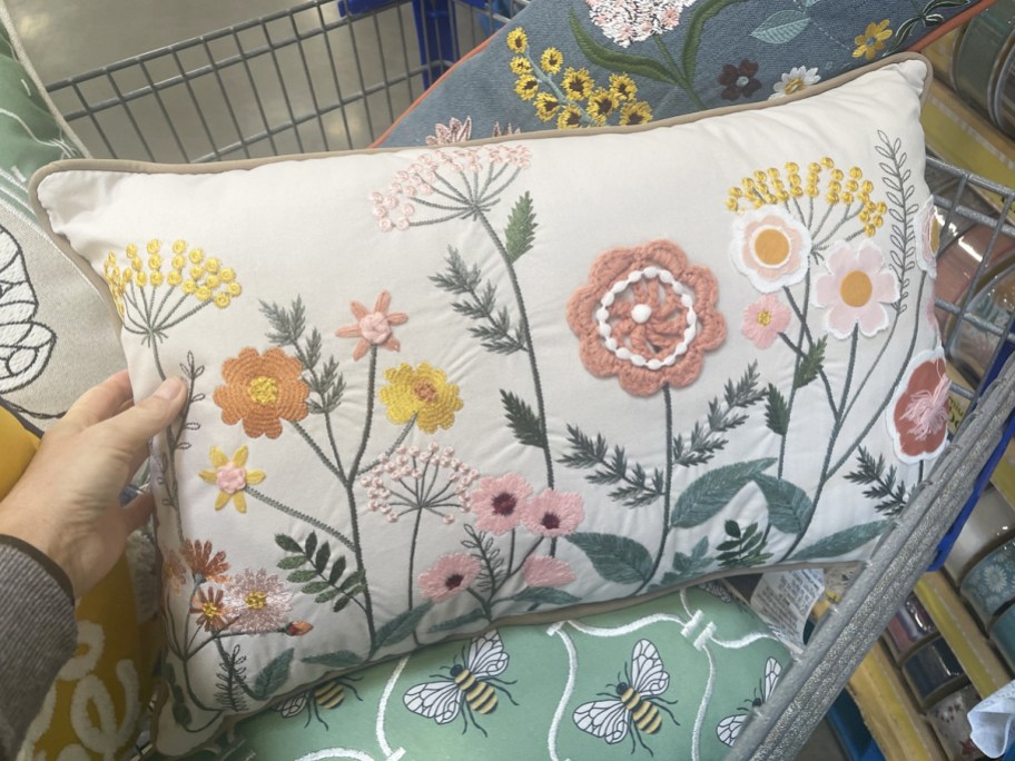 hand holding a throw pillow with embroidered flowers