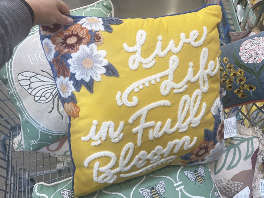 hand holding yellow throw pillow that says "live life in full bloom"
