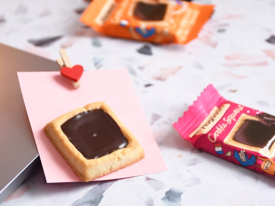 square cookie topped with chocolate on a pink piece of paper