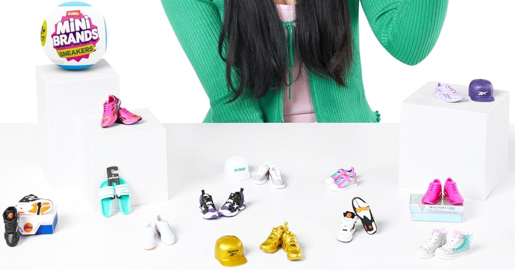 girl sitting in front of table filled with mini pairs of sneakers and hats