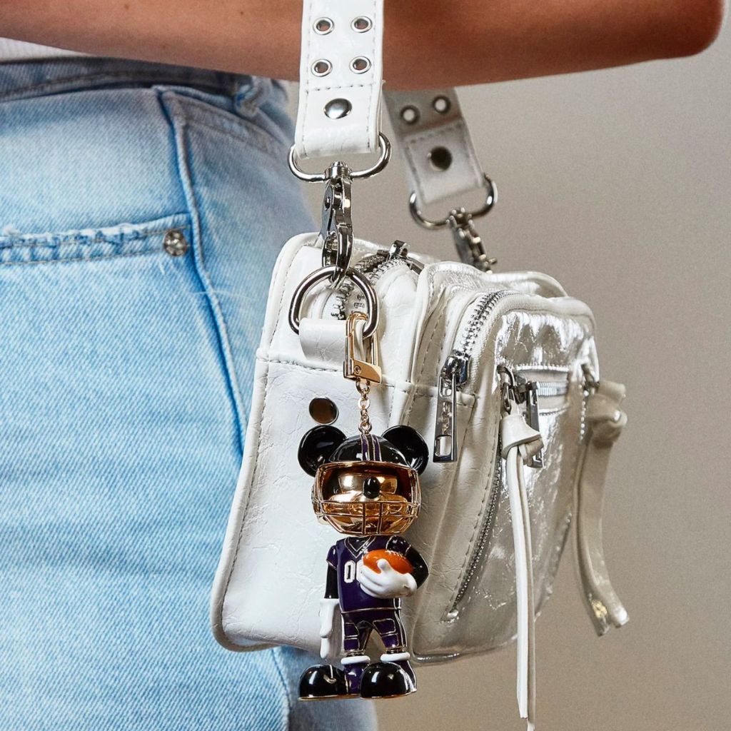  mickey mouse bag charm hanging from a small white top handle hand bag