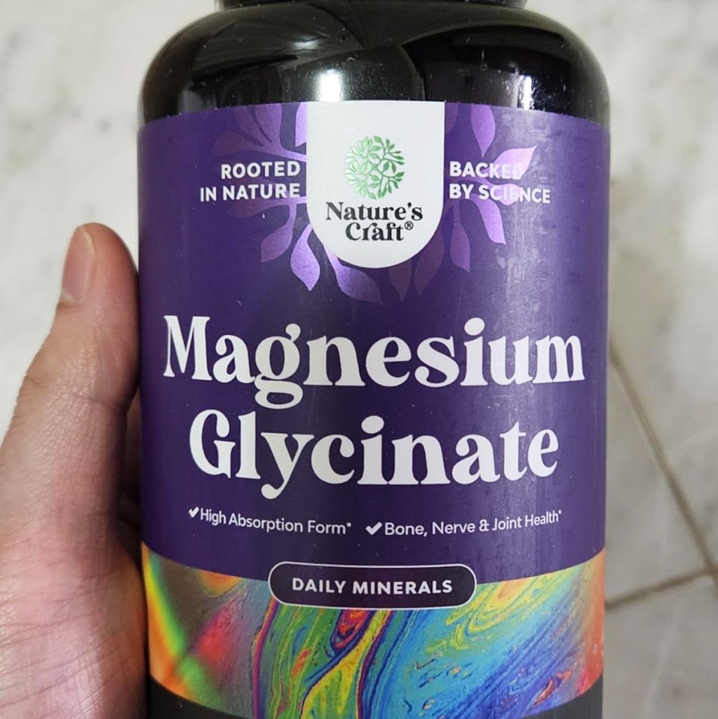 hand holding a bottle of Nature's Craft Magnesium Glycinate Capsules