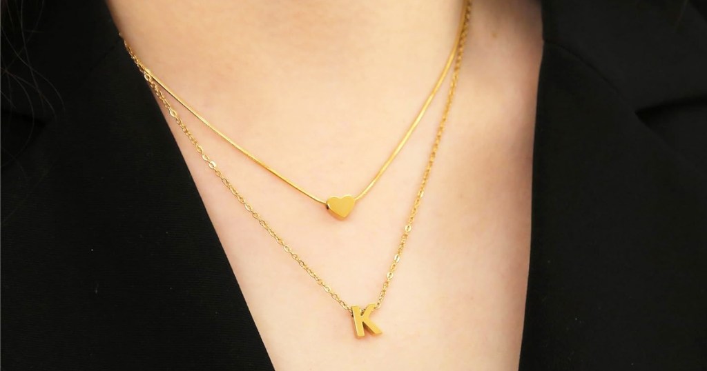 woman wearing gold initial letter K necklace layered with small heart pendant necklace