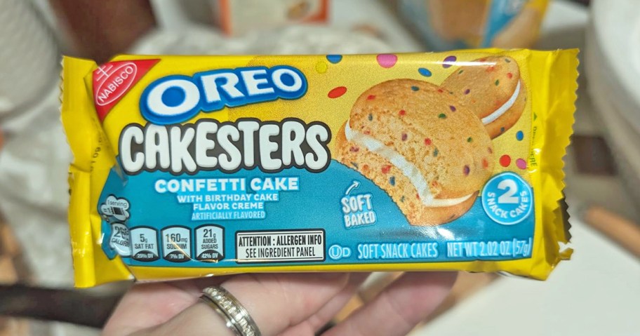 hand holding a yellow and blue pack of OREO Cakesters Confetti Cake cookies