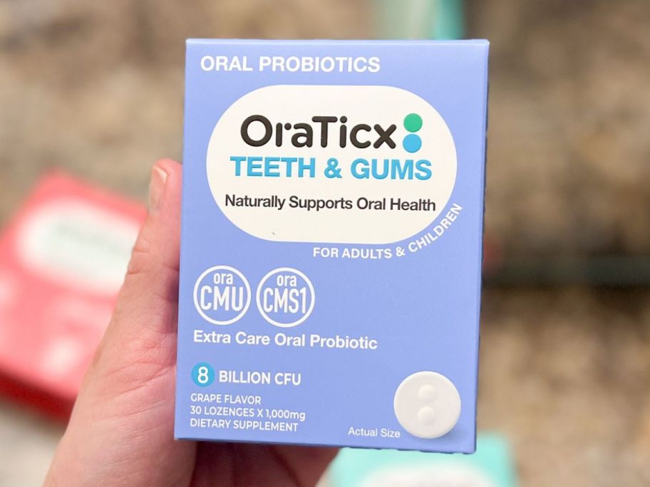 Hand holding a boc of OraTicx Teeth & Gums formula