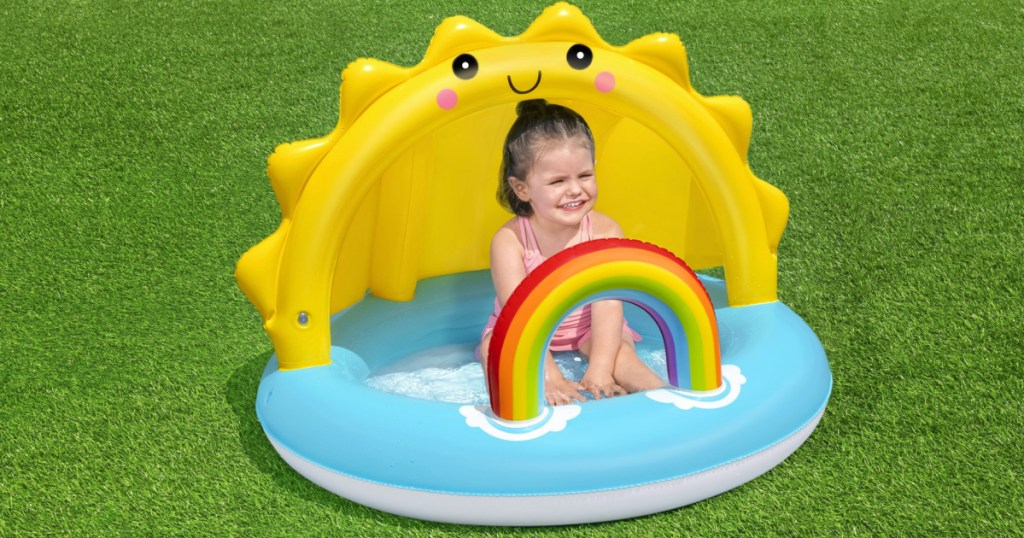little girl sitting in baby pool with sun and rainbow