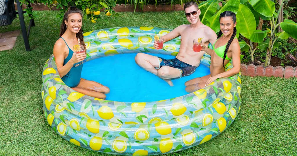 three people sitting in a lemon-print inflatable pool