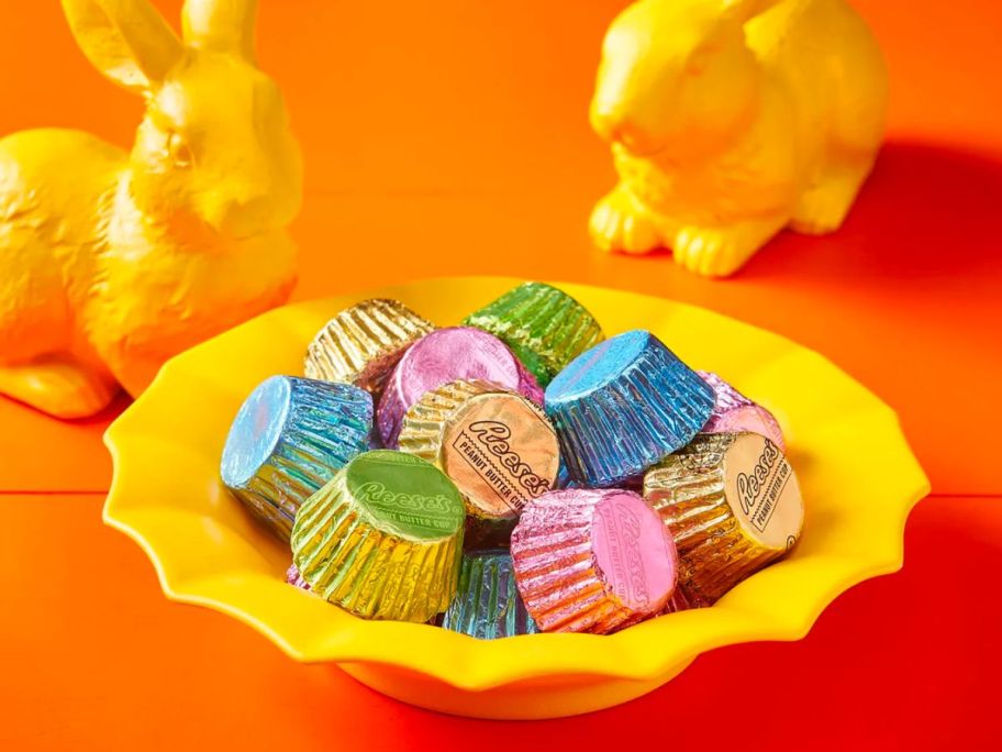 a small yellow fluted bowl filled with REESE'S Miniatures Milk Chocolate Peanut Butter Cups in pastel wrappers