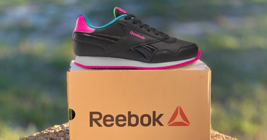 black and pink sneaker on top of a reebok shoe box