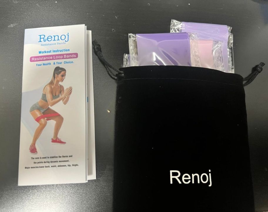 A Renoj Resistance Band Bag and Booklet on a bed