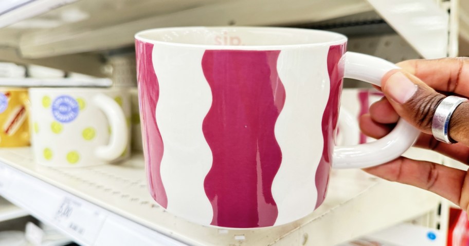 hand holding up a purple and white wavy print coffee mug