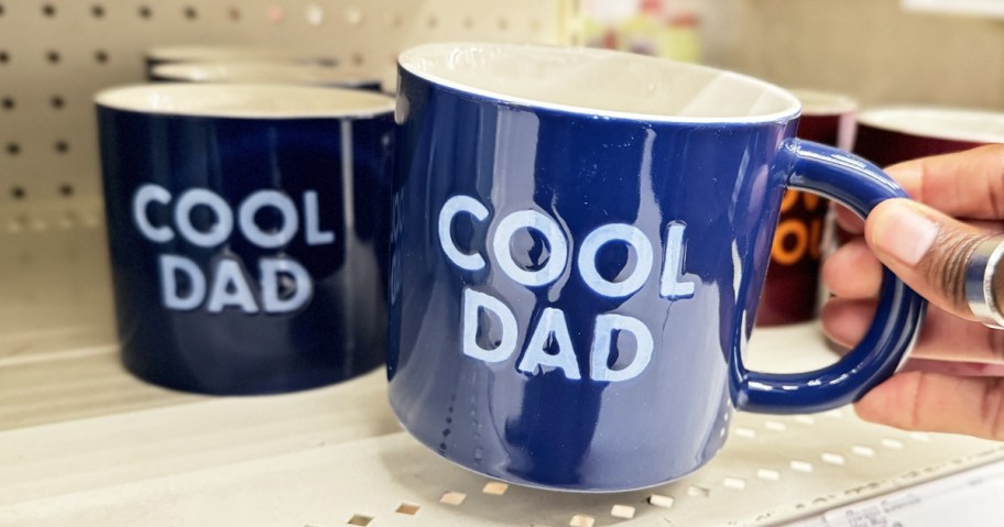 hand holding a blue mug that says "Cool Dad"