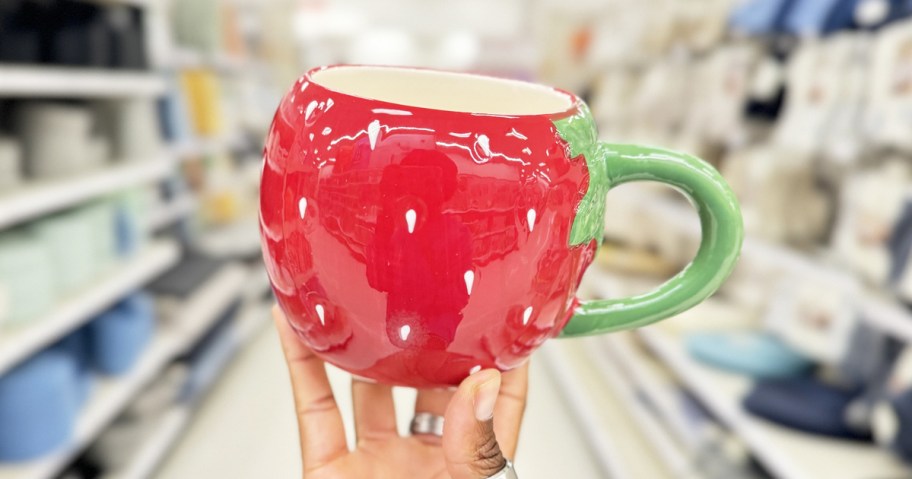 hand holding up a red strawberry mug