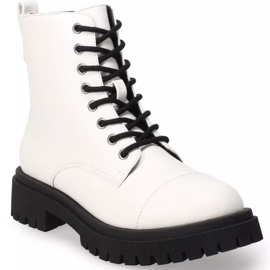 a white combat boot with a black lug sole and laces