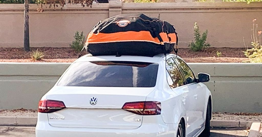 white car with a black and orange car rooftop carrier bag on top