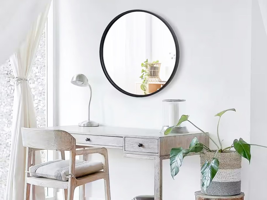 round wall mirror with black frame above vanity