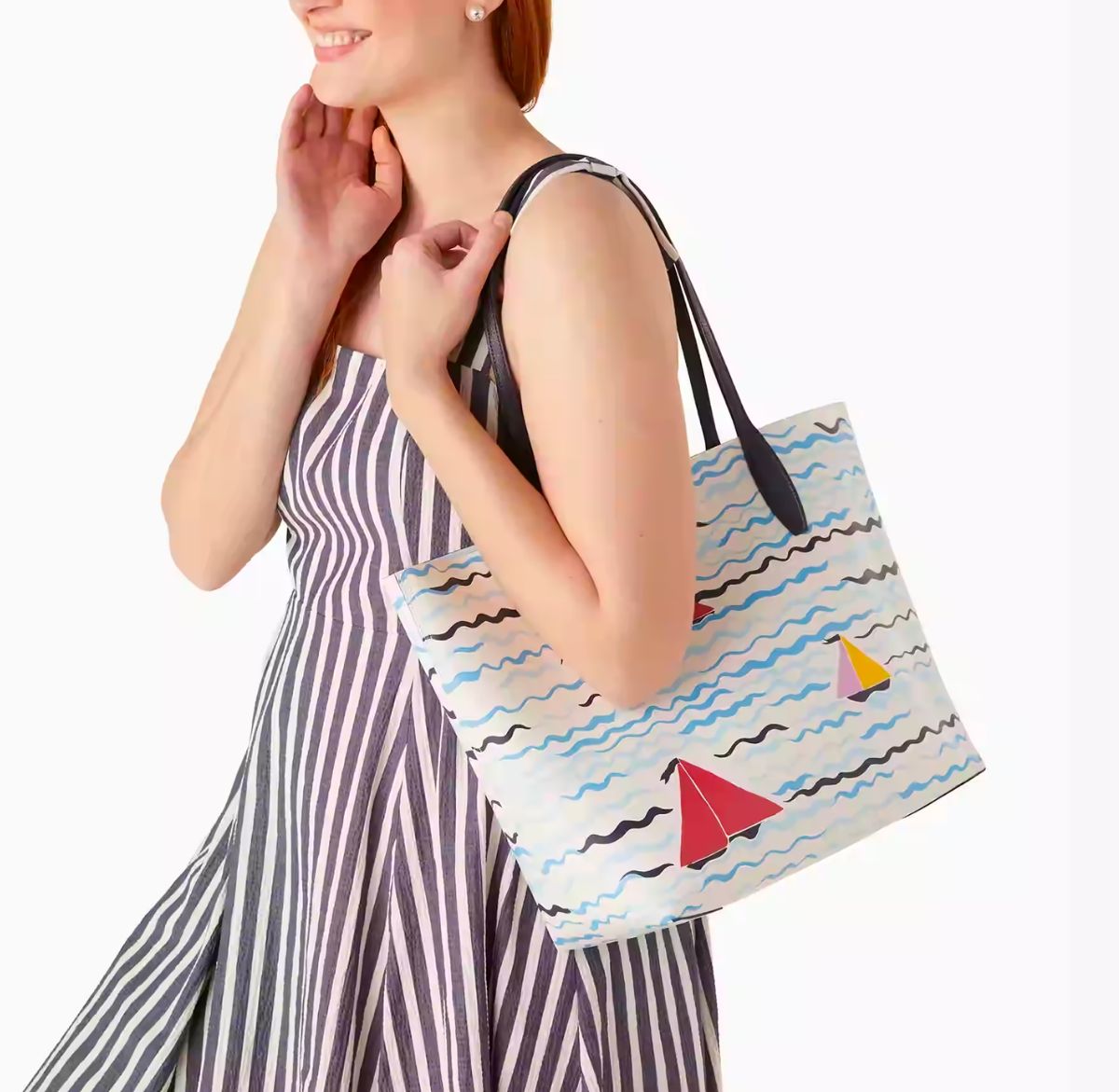 a woman in a sun dress with a large tote on her shoulder featuring a sail boat print