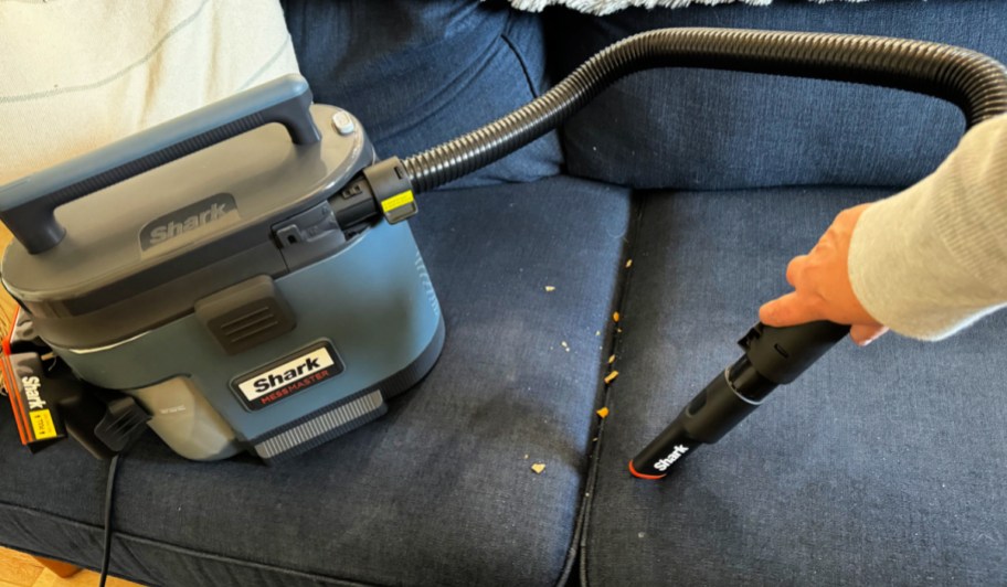 woman using Shark Mess Master vacuum to clean up mess on blue couch