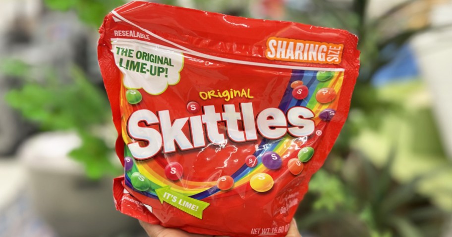hand holding large red bag of skittles