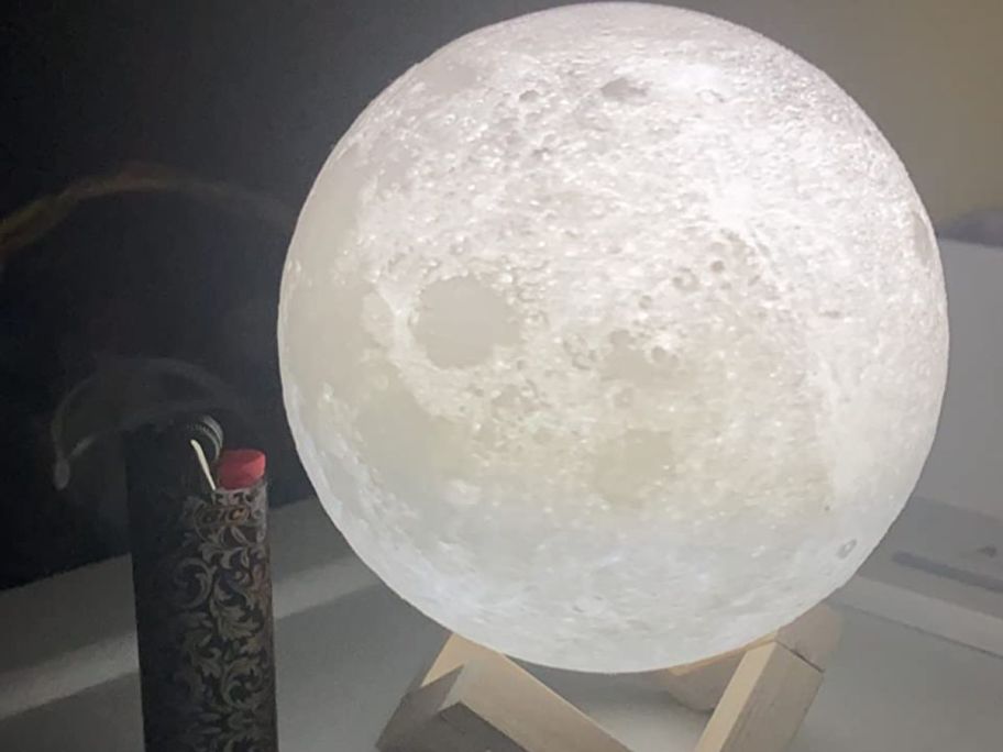 A small moon lamp next to a BIC liter