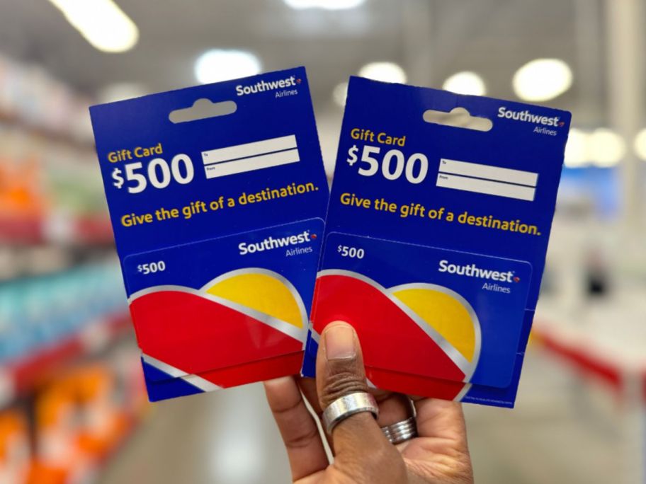 A hand holding two Southwest Airline Gift Cards