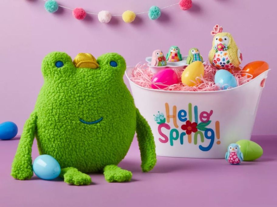 A Spritz Frog Easter pillow next to a bucket of Eggs with Featherly Friends on it